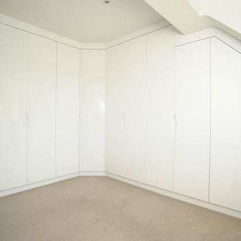 Fitted white glossy wardrobe for angled ceiling
